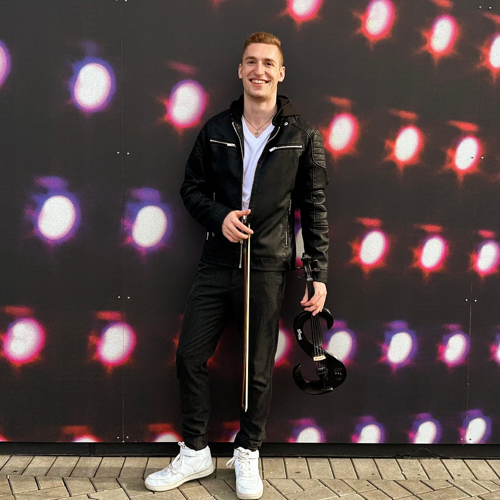 Paul Kolodziej violinist and musical artist at MTV club Düsseldorf infront of a photo wall