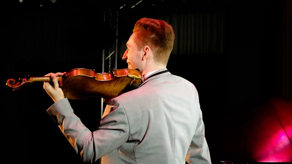 Paul Kolodziej (musical artist and violinist) at a concert with his violin on stage